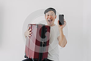 Surprise and wow face of Asian man holding up a suitcase and showing the mobile phone application display.