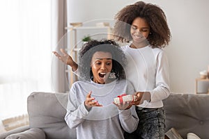 Surprised African American mother receiving gift from teenage daughter