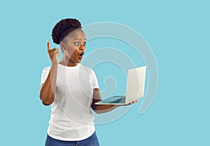 Surprised african american woman having an idea looking at screen of laptop on blue background.