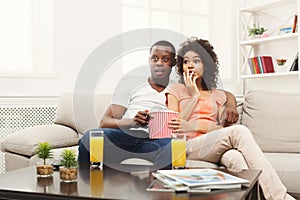 Surprised african-american young couple watching TV at home