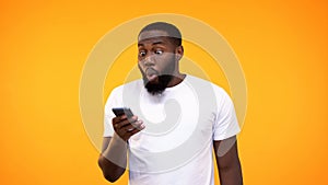 Surprised afro-american guy looking at phone screen, lottery winner, betting app