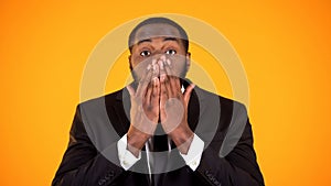 Surprised afro-american male in businesswear closing face with hands, promotion photo