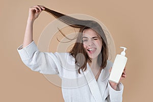 Surprised amazed girl applying hair conditioner. Young woman applying hair mask.