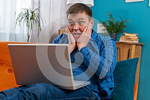 Surprised amazed man using laptop computer, receive mail good news message wow shocked win app game