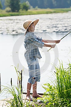 Surprised angler boy is throwing bait of handmade fishing rod