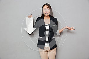 Surprised asian business woman shrugs her shoulders and pointing