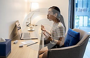 Surprised asian student watching laptop computer with wide eyes and fling arms up after received great news,good income,earning