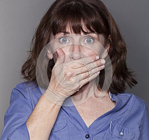 Surprised attractive mature woman hiding her mouth