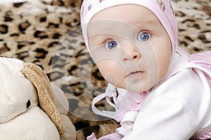 Surprised baby in a cap with a soft toy