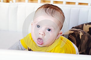 surprised baby lies on a stomach in a bed