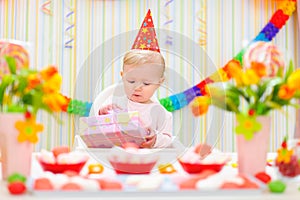 Surprised baby looking on gift on first birthday