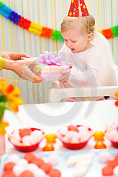 Surprised baby receiving present on first birthday