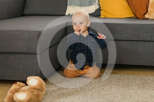 Surprised baby sitting on carpet. Child& x27;s eyes widened and mouth opened in amazement. Copy space for text