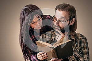 Surprised bearded man with glasses reading book while black-haired girl watches what he reads