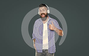 surprised bearded man listen to music in headphones. point finger