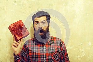 Surprised bearded man with red gift box with bow