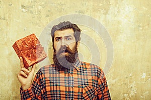 Surprised bearded man with red gift box with bow