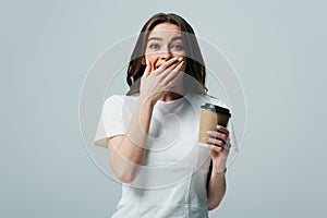 Surprised beautiful girl in white t-shirt with paper cup isolated on grey