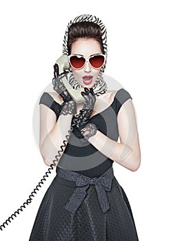 Surprised beautiful woman in pin-up style with retro telephone