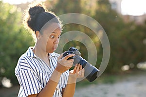 Surprised black photograper checking result on camera photo