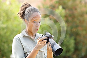 Surprised black photographer checking photos on camera