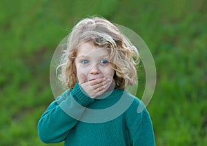 Surprised blond child covering his mouth