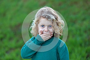 Surprised blond child covering his mouth