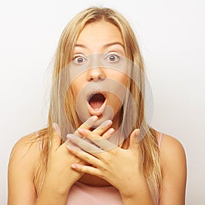 Surprised blond girl holding her head in amazement and open-mouthed.