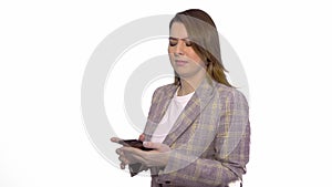 Surprised blonde girl texting on mobile phone while standing isolated over white background