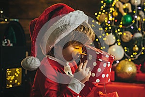 Surprised boy child open christmas gift near christmas tree. Lovely baby enjoy christmas. Funny kids face closeup.