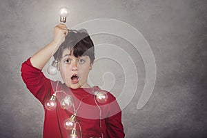 Surprised boy with light bulbs on gray background