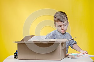 Surprised boy looking opening a box and gasping in surprise seeing the content of the box while recording an unboxing vlog