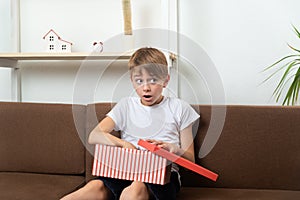 Surprised boy opens the gift box and looks around. Suddenness