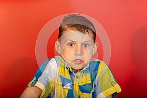 The surprised boy shrugs and does not know what to do, on a red background