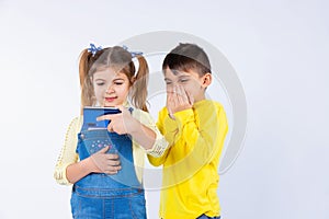 Surprised boy on a white background and next to a girl with a smartphone in her hands. Side space.