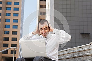 surprised business man sitting on steps with laptop hods his head