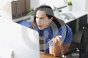 Surprised business woman looking at computer screen in office