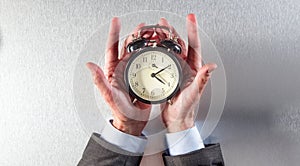 Surprised businessman hands holding an alarm clock for time strategy