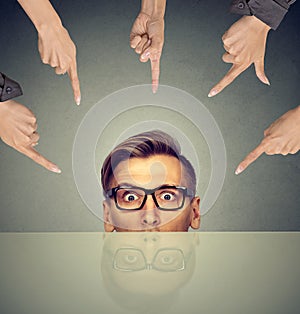 Surprised businessman peeking from under the table