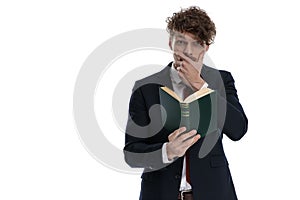 Surprised businessman reading book and covering his mouth
