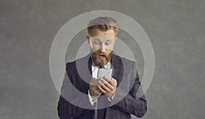 Surprised businessman received shocked news on mobile phone studio portrait