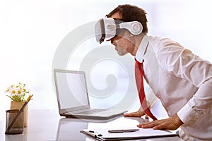 Surprised businessman using virtual reality glasses resting on h