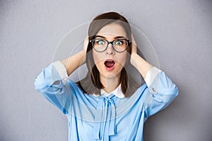 Surprised businesswoman with glasses over gray background