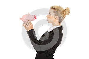 Surprised businesswoman holding a piggybank