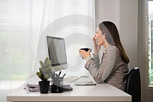 Surprised businesswoman sitting at her workplace and looking at computer monitor