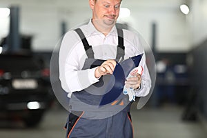 Surprised car service worker is holding a blue clipboard