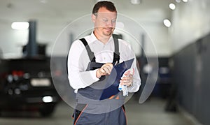 Surprised car service worker is holding a blue clipboard