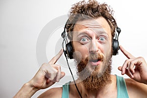 Surprised caucasian man with curly hair and beard stares in amazement at camera