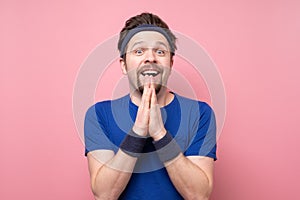 Surprised caucasian man dressed in sportswear gestures with surpise and hope