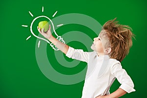 Surprised child against green chalkboard in class